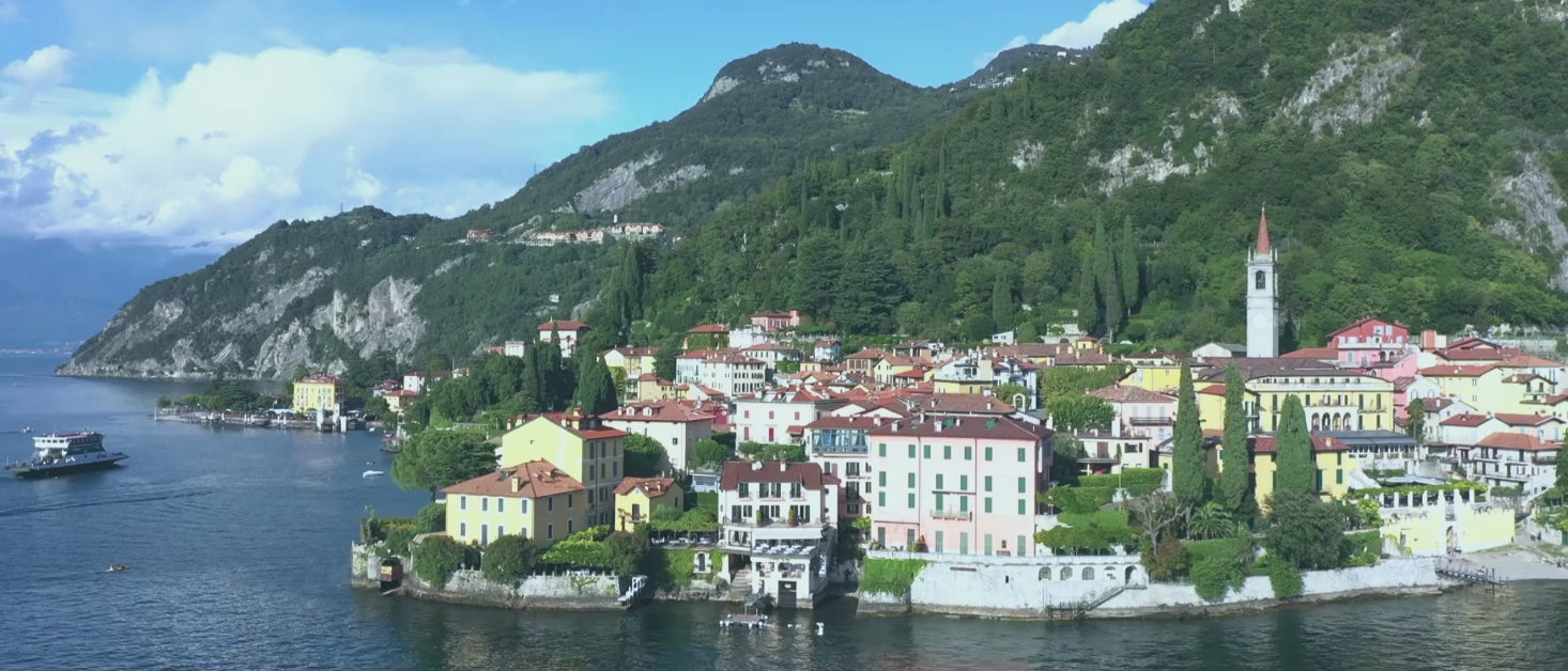 Camera pans across the shoreline of Lake Como with mountains and villas in the backdrop